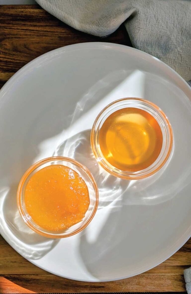 Two jars of Crystallised Honey and honey on plate