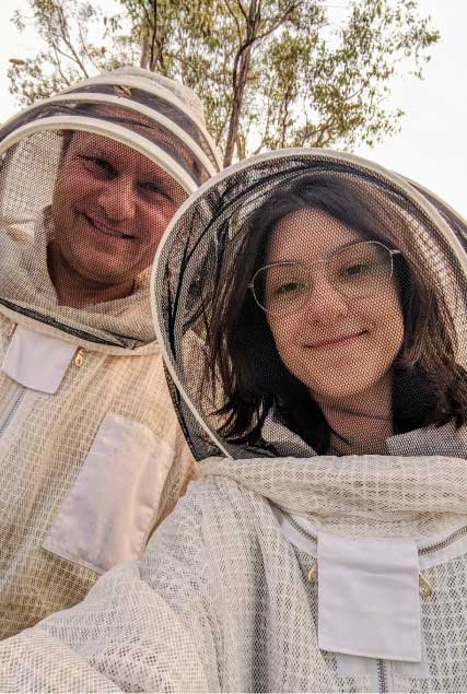 Two beekeepers smiling in protective gear